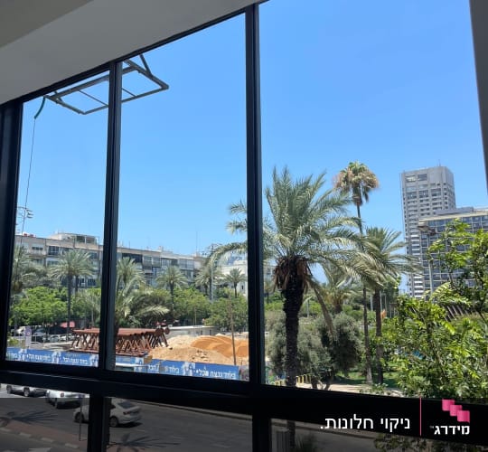 בקבוק תרסיס ניקוי על שולחן ליד חלון